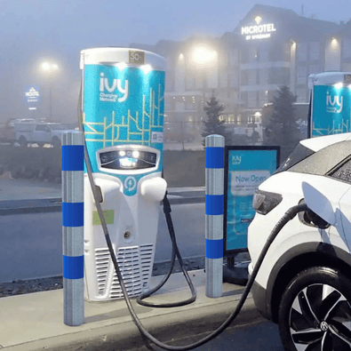 Verzinkt-blauw aanrijdbeveiliging paal Ø76-102 mm bij een laadpaal, beschermt een witte auto.