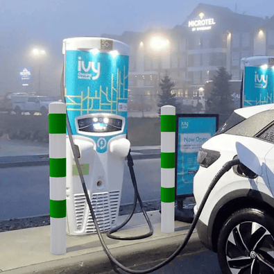 Wit-groene aanrijdbeveiligingspalen (Ø76-102 mm) beschermen een laadpaal en elektrische auto.