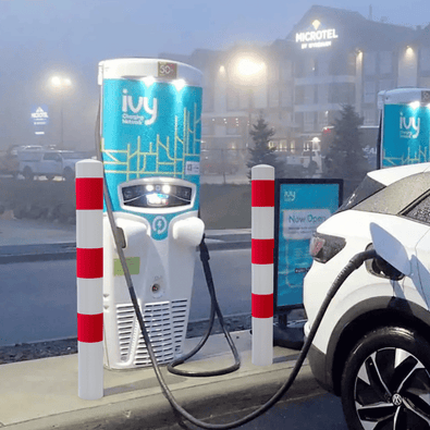 Witte en rood gestreepte aanrijdbeveiliging palen beschermen een laadpaal en elektrische auto.