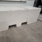 Lichtgrijze betonnen afzetblok met lepelgaten, 820 kg, op een betonnen vloer.