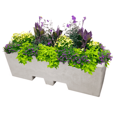 Lichtgrijze betonnen afzetblok/bloembak met lepelgaten, gevuld met diverse bloeiende planten.