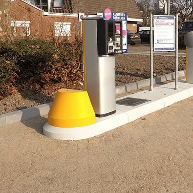 Gele aanrijdbeveiliging van kunststof, kegelvormig, naast een parkeerautomaat op een verkeerseiland.