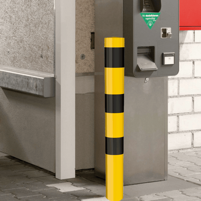 Geel-zwarte afzetpaal Ø102 mm, staand voor een betaalautomaat, voor betonverankering of voetplaatmontage.
