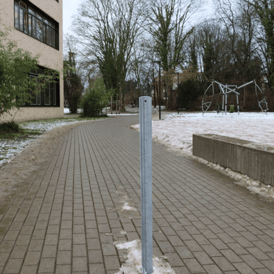 Gegalvaniseerde stalen afzetpaal Ø60 mm, staand op een bestraat pad met sneeuw, ideaal voor betonverankering.