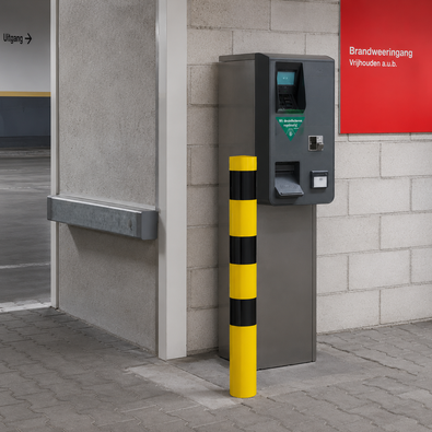 Geel-zwarte afzetpaal Ø102 mm, staand voor een betaalautomaat, voor betonverankering of voetplaatmontage.