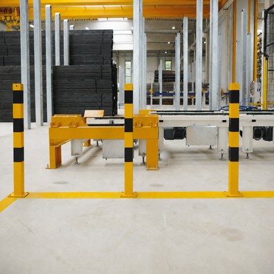 Afzetpaal 70x70mm geel-zwart voor verankering in beton geplaatst in een bedrijfshal naast transportband