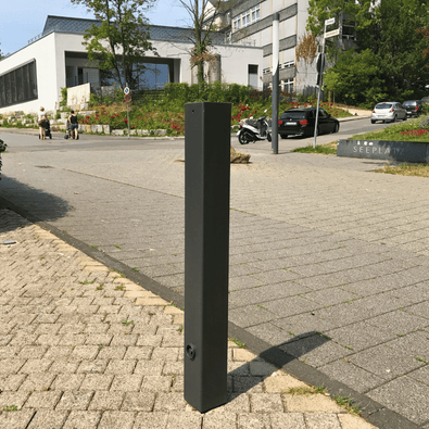 Zwarte design afzetpaal, 80x80 mm met vlakke kop, staand op een grijze tegelstoep.