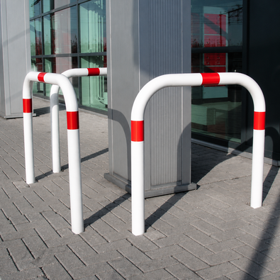 Wit-rode beschermbeugel Ø60 mm, U-vormig, verankerd in betonnen bestrating.