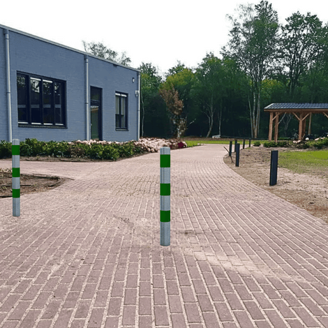 Verzinkt-groene beschermpalen Ø102 mm op een bestrate oprit bij een gebouw.
