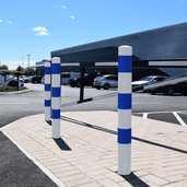 Witte en blauwe beschermpalen (Ø102 mm) op een parkeerplaats, geschikt voor betonverankering.