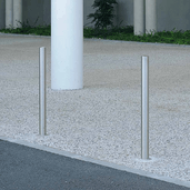 Twee RVS beschermpalen Ø60 mm, geborsteld staal, verankerd in een betonnen ondergrond.