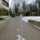 Verzinkt stalen beschermpaal Ø60 mm op een bestrate ondergrond met sneeuw, ideaal voor betonverankering.