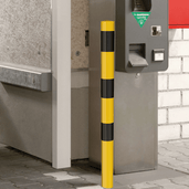 Gele en zwarte beschermpaal Ø76 mm, staand naast een betaalautomaat, voor betonverankering.
