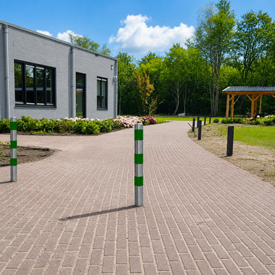 Verzinkt-groene beschermpalen Ø102 mm op een bestrate oprit bij een gebouw.