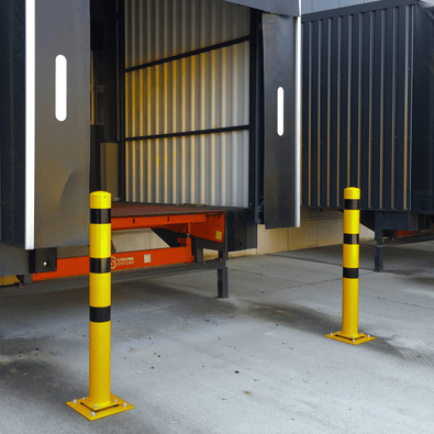 Twee gele en zwart gestreepte beschermpalen op flexibele voetplaten voor een laadperron.