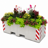 Grijze betonnen afzetblok/bloembak met lepelgaten, gevuld met diverse bloemen en planten, voorzien van reflecterende strepen.
