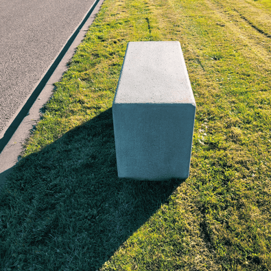 Antraciet betonnen poef, 1000x400x500 mm, rechthoekig, op gras naast een pad.