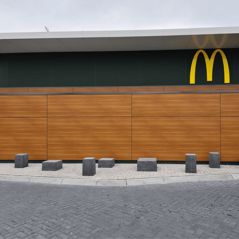 Antraciet betonnen poef, 450x450x650 mm, robuust en modern, ideaal voor openbare ruimtes.