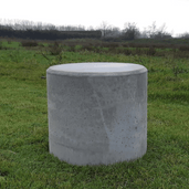Antraciet betonnen poef, Ø500x600 mm, cilindervormig, staand in gras.