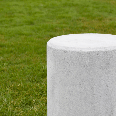 Grijze betonnen poef, Ø500x600 mm, op een groen gazon.