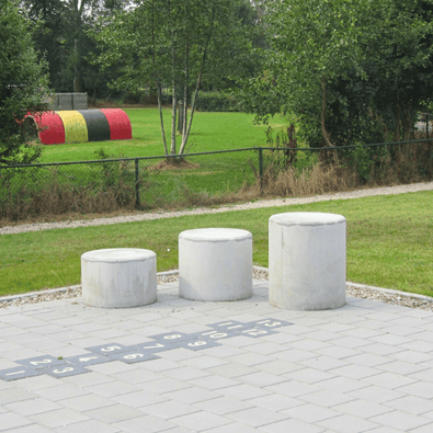 Drie ronde antraciet betonnen poefs in verschillende maten op een speelplaats.