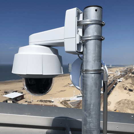 Verzinkt stalen dakmast met witte beveiligingscamera, gemonteerd op een dak met strandzicht.