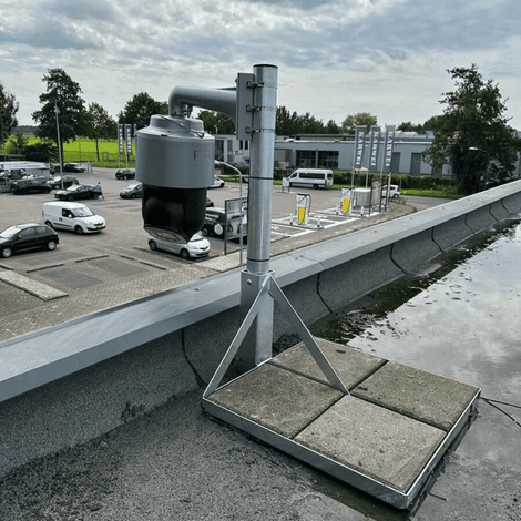 Verzinkt stalen dakmast met tegelvoet, ondersteunt een grijze camera op een plat dak.