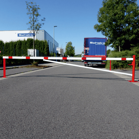Rood-witte draaiboom, 300-600 cm, met 2 vangpalen voor betonverankering, op een bedrijfsterrein.