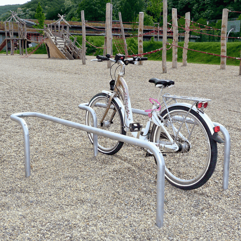 Verzinkt stalen fietsbeugel met gebogen hoek, buis Ø42 mm, met een witte fiets op een grindplein.