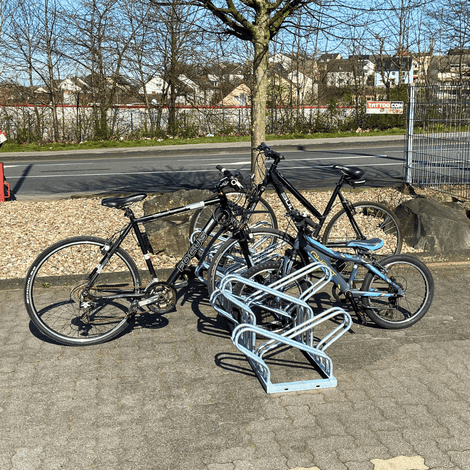 Dubbelzijdig fietsenrek van verzinkt staal, geschikt voor 6 fietsen, met 3 fietsen geparkeerd.