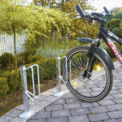 Verzinkt stalen individueel fietsenrek voor vloermontage, met een fiets geparkeerd op een bestrate ondergrond.