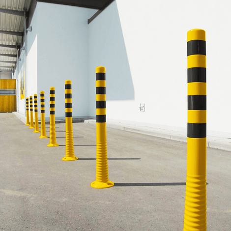 Flexibele geel-zwarte paaltjes in verschillende hoogtes, staand op een rij op een betonnen ondergrond.