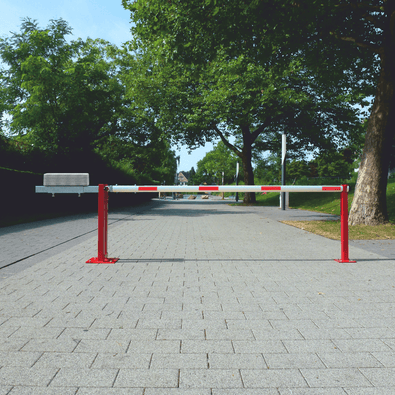 Handmatige slagboom, rood-wit gestreept, met contragewicht en vangpaal op een geplaveide weg.