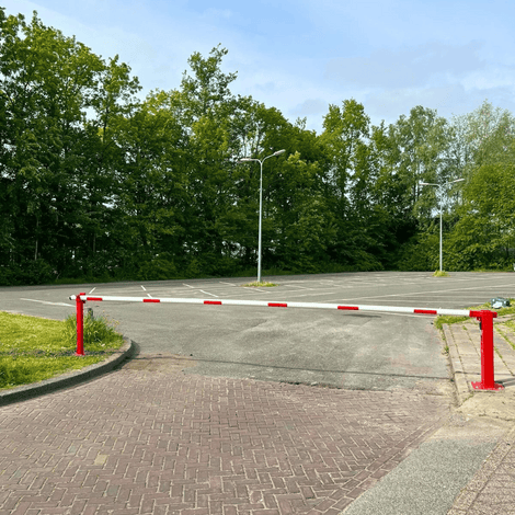 Rood-witte handmatige slagboom met vangpaal, geïnstalleerd op een parkeerplaats.
