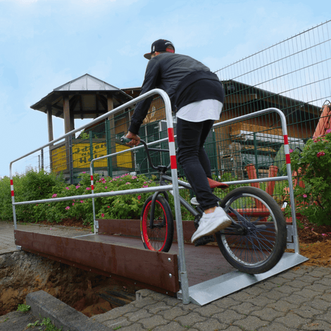 Houten loopbrug met stalen frame en zijgeleiding, gebruikt door een fietser.