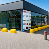 Gele betonnen jumboblokken van 330 kg van Oud Hollands stampbeton als aanrijdbeveiliging voor de gevel van een modern bedrijfspand.