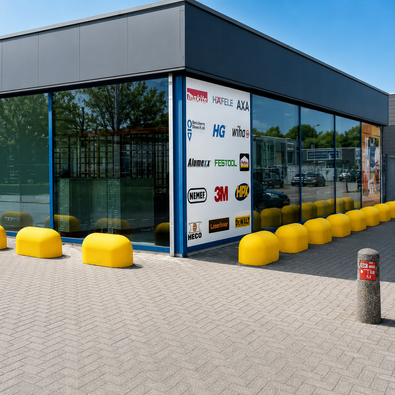 Gele betonnen jumboblokken van 330 kg van Oud Hollands stampbeton als aanrijdbeveiliging voor de gevel van een modern bedrijfspand.