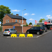 Drie gele Jumboblokken van Oud Hollands stampbeton met lepelgaten, gebruikt als parkeerbegrenzers.