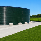 Grijze Jumboblokken van Oud Hollands stampbeton met hijsoog, geplaatst bij een grote wateropslagtank.