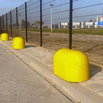 Drie gele Jumboblokken van Oud Hollands stampbeton langs een hekwerk op een industrieterrein.