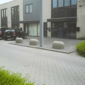 Drie grijze Jumboblokken van Oud Hollands stampbeton, strategisch geplaatst op een bestrate parkeerplaats.