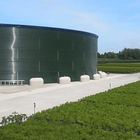 Wit Jumboblok van Oud Hollands stampbeton met hijsoog, 330 kg, ondersteunt een grote groene watertank.