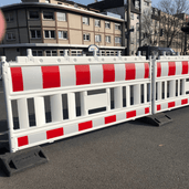 Wit kunststof afzethek EURO 2 met rode reflecterende strepen op zwarte voeten, staand op asfalt.