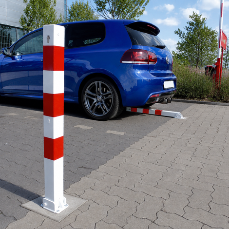 Wit-rode neerklapbare afzetpaal 70x70 mm met betonvoet, staand en neergeklapt bij een parkeerplaats.