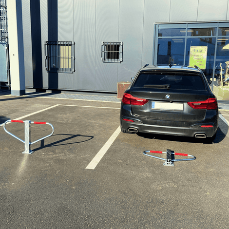 Wit-rode parkeerbeugel in open en gesloten positie op asfalt, met zwarte auto op parkeerplaats.