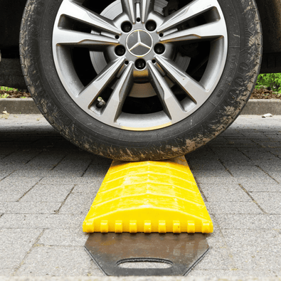 Oprolbare gele verkeersdrempel van 300x25x3 cm onder een autoband, op een grijze tegelvloer.