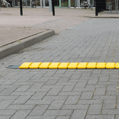 Oprolbare gele verkeersdrempel van 300 cm lang op grijze bestrating.