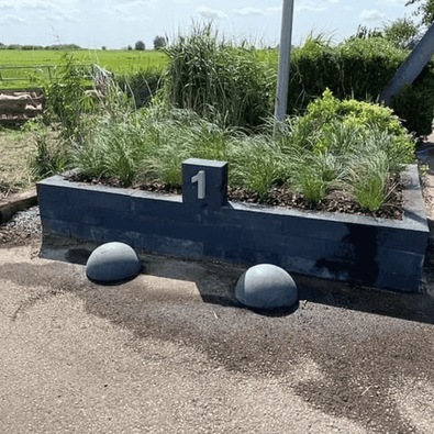 Twee antraciet betonnen parkeerbollen (Ø400 mm) voor een plantenbak met nummer 1.
