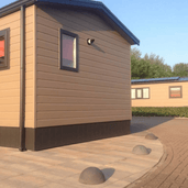 Antraciet betonnen parkeerbollen (Ø500 mm) zonder voet, geplaatst op een terras naast een chalet.