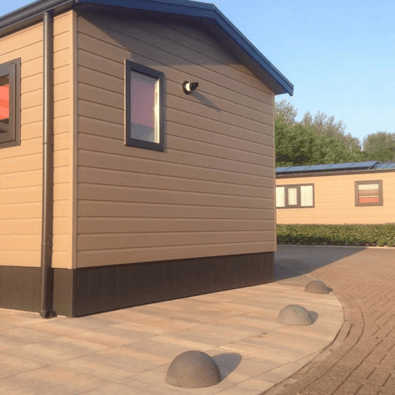 Antraciet betonnen parkeerbollen (Ø500 mm) zonder voet, geplaatst op een terras naast een chalet.